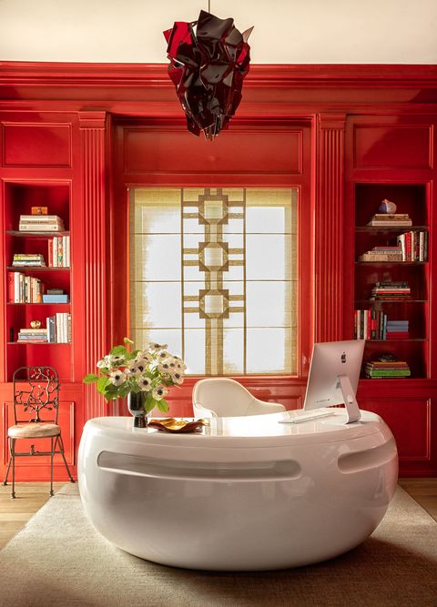 kidney shaped white desk in a room with red lacquered walls