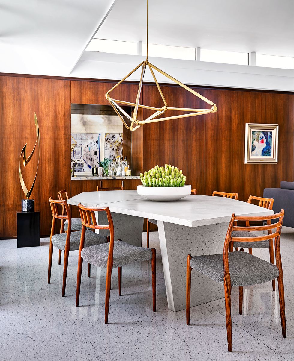 wood paneled dining room with large triagular pendant over white table