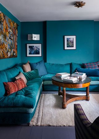 colorful living area with teal wraparound sofa and matching wall color and round coffee table