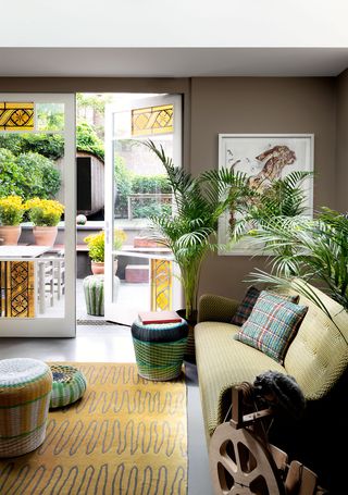 garden room with door to atrium, potted plants, and greenish yellow sofa and accessories