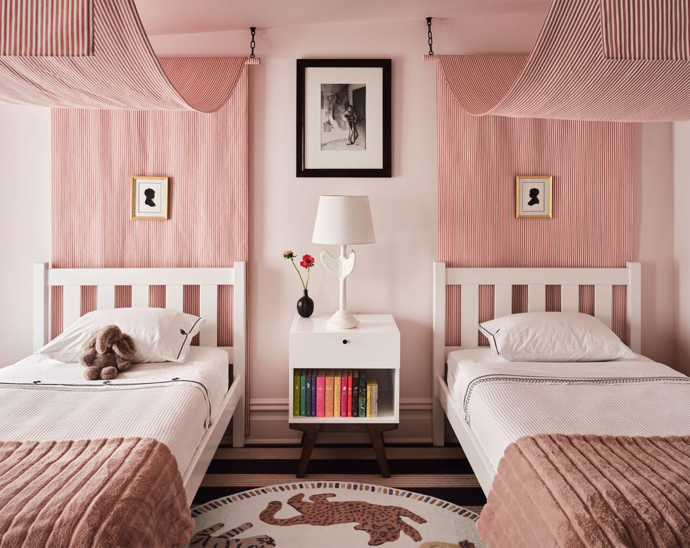 twin beds with a pink canopies and little framed silhouettes over them