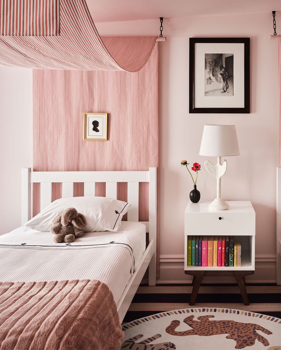 twin beds with a pink canopies and little framed silhouettes over them