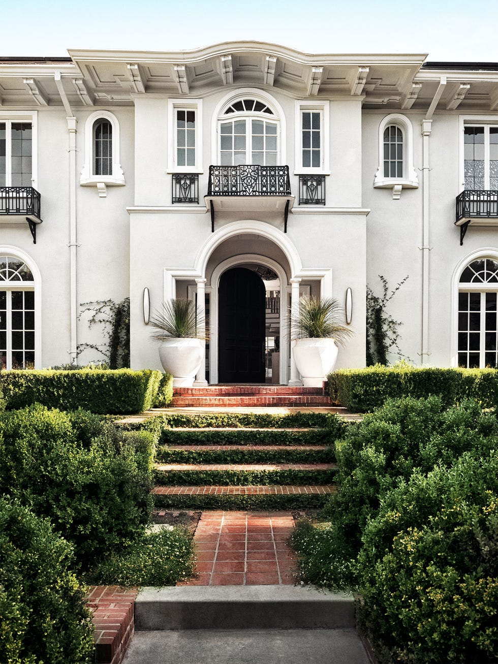 palatial white building with a red terracotta walkway and landscaping on the sides