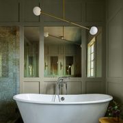 deep standalone white tub in a smallish space with paneled wall with mirrors behind it