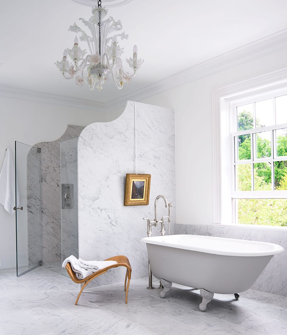 a white bathroom with a tub and a chair