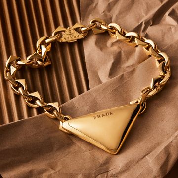 chunky gold necklack with a large soft edged trademark triangle at center inscribed with the prada logo