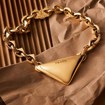 chunky gold necklack with a large soft edged trademark triangle at center inscribed with the prada logo