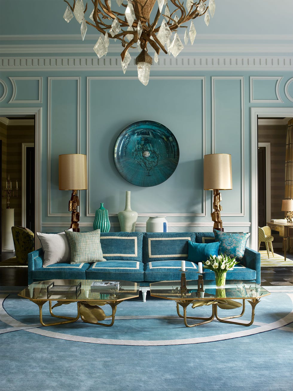 living space in all blues with a dark blue sofa with white interior trimming and two matching gold leafed glass topped cockta