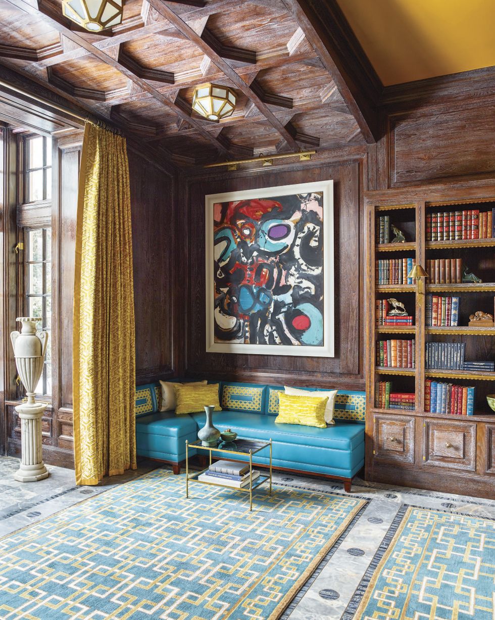 Library with high ceilings, blue banquette, geometric rug, and giant amphora