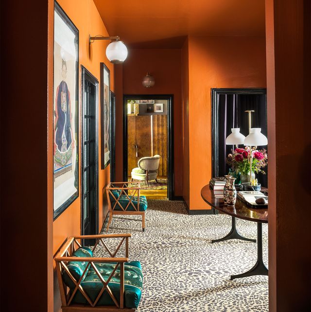 orange living room with rattan chairs and leopard pattern carpet and art on walls