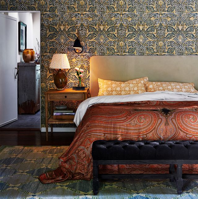 bedroom with detailed wallpaper bed and bench at the foot of the bed