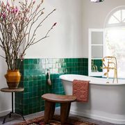 a bathroom with a standalone tub and green tile wall