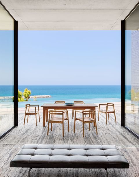 we open on a low black leather quilted bench and then move out to a light wood table and chairs as large floor to ceiling glass doors open up and there is the mediterranean right at your fingertips