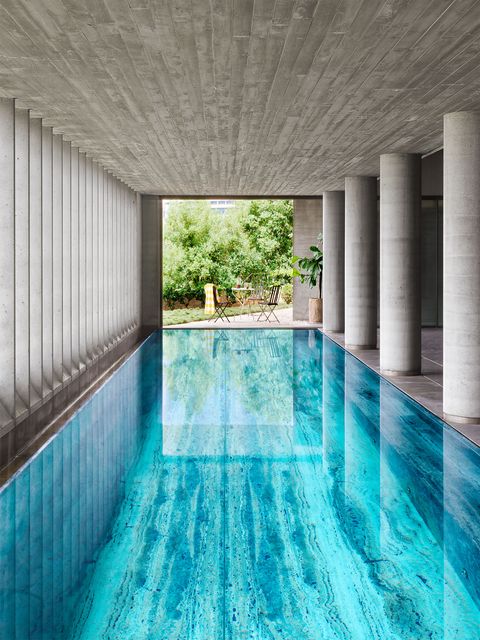 a long view of a oh so clear blue with sharp undisturbed reflections in ground pool in a columned terrace area