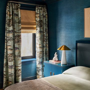 blue room with netural beige bed with dark blue headboard and blue side table and toil curtains