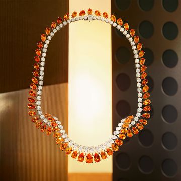pear shaped diamond and orange spessarite stones in a long necklace against a metal background