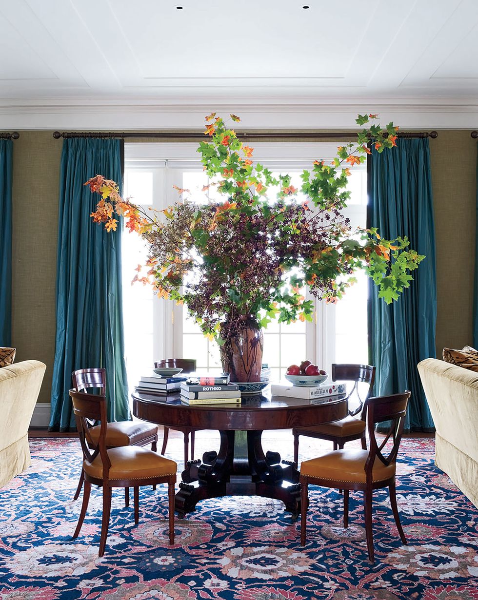a 19th century center table in the living room is surrounded with leather upholstered biedermeier chairs