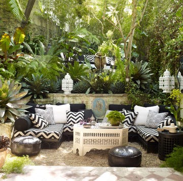 verdant outdoor room with poofs and lanterns and seating area and terra cotta floor