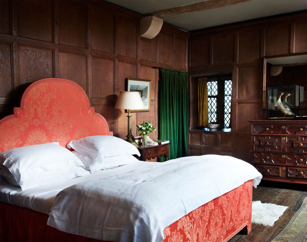 A paneled bedroom with a large bed with a red headboard