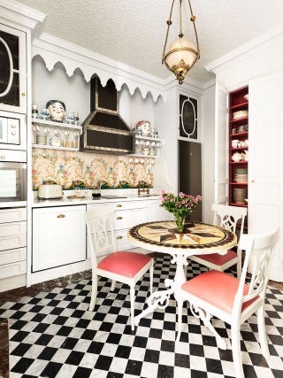 kitchen with black and white checked floor, small table, floral backsplash