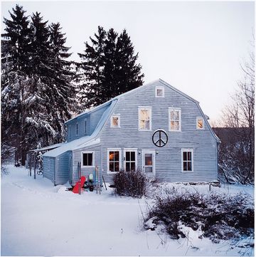 old fashioned looking farmhouse set in snow and large pine trees