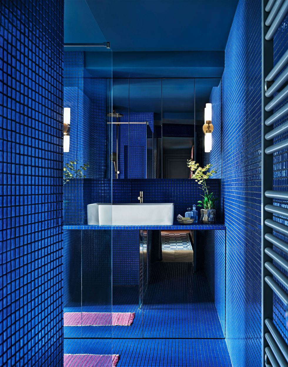 all vibrant blue tiled bathroom with a small pink rug