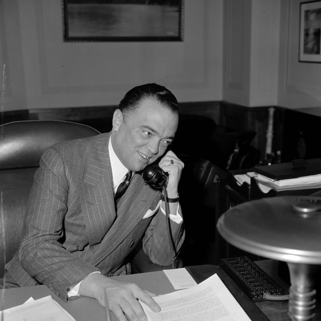 j edgar hoover sitting at a desk and talking on the phone