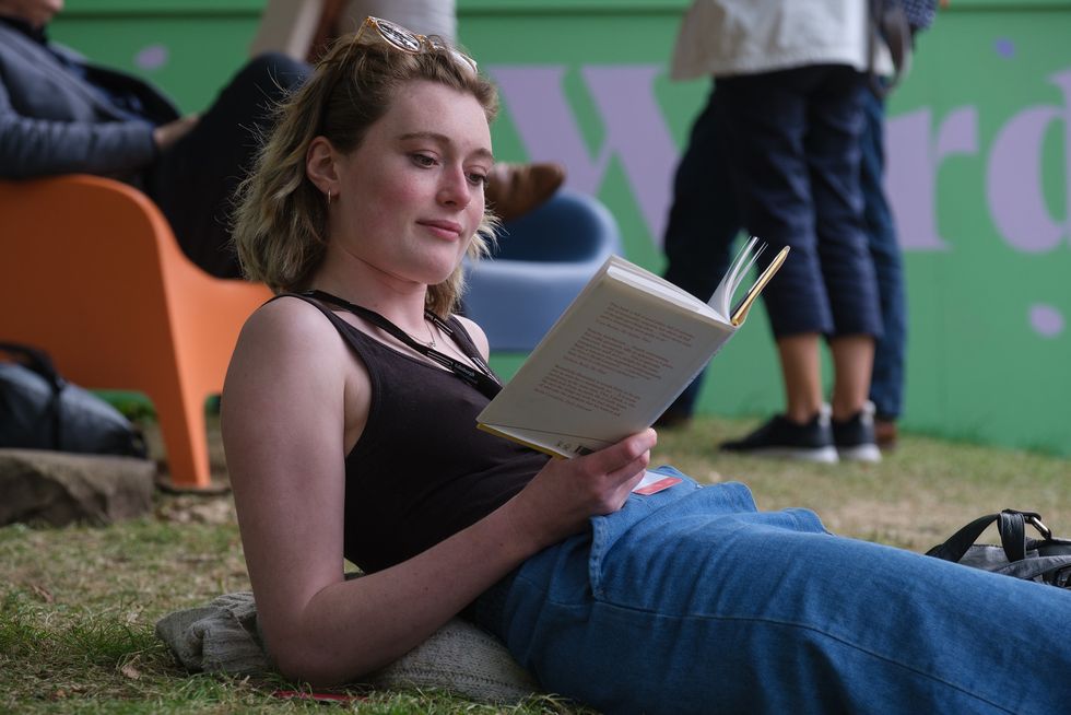 a person sitting on the grass reading a book
