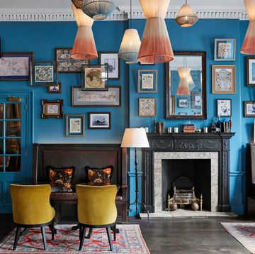 a living room withblue walls yellow chairs and a fireplace