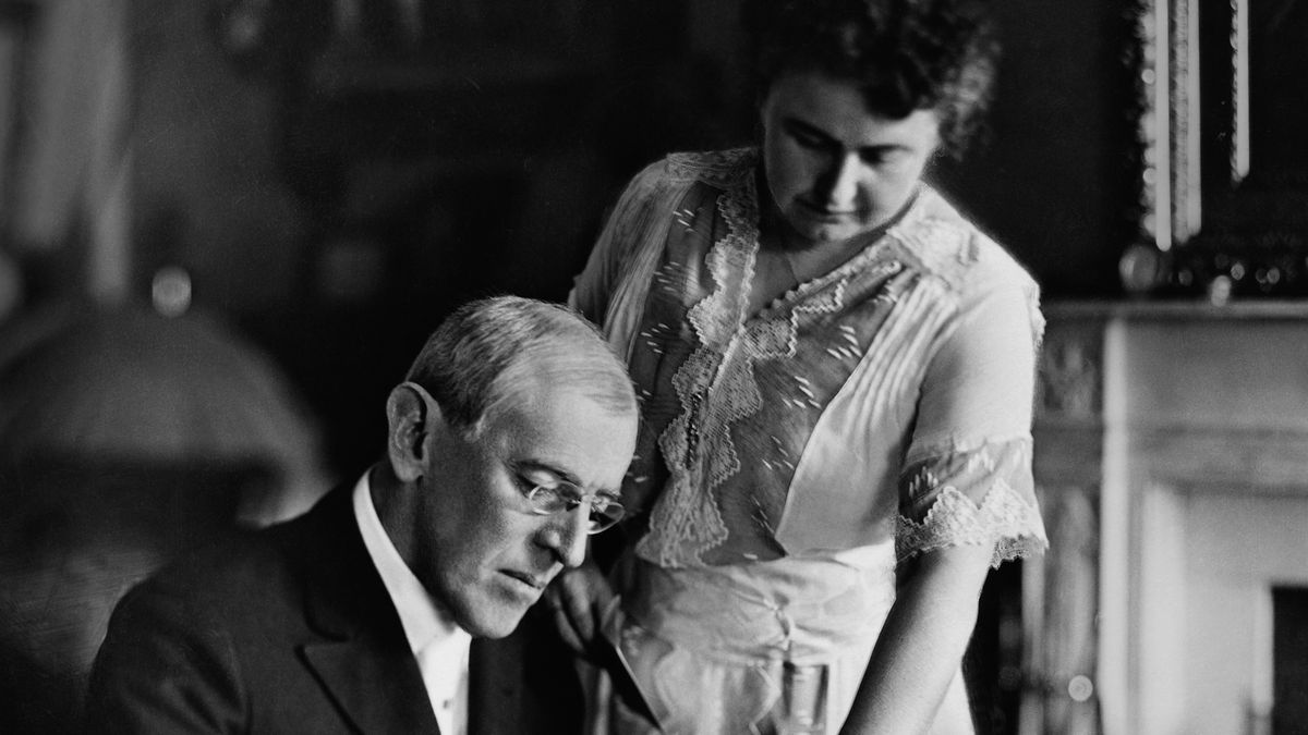 American politician Woodrow Wilson (1856 - 1924), President of the United States from 1913-1921, goes over papers at his desk as his second wife Edith Bolling Galt Wilson (1872 - 1961) looks on, mid 1910s. Edith was often referred to as "secret president" because of the important role she played in Wilson's presidency during his long and debilitating illness following a stroke. (Photo by Stock Montage/Getty Images)