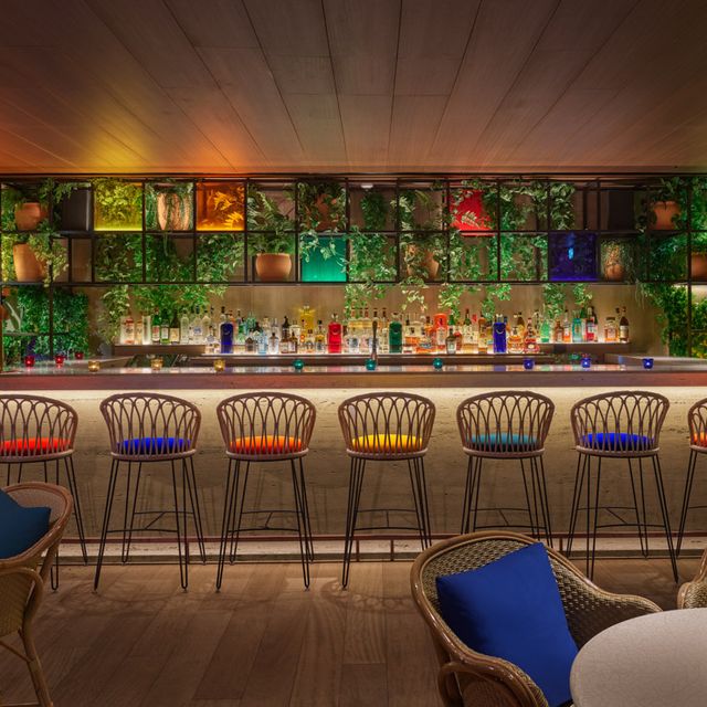 barra de bar con taburetes de colores y bebidas al fondo