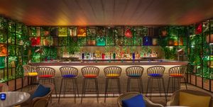 barra de bar con taburetes de colores y bebidas al fondo