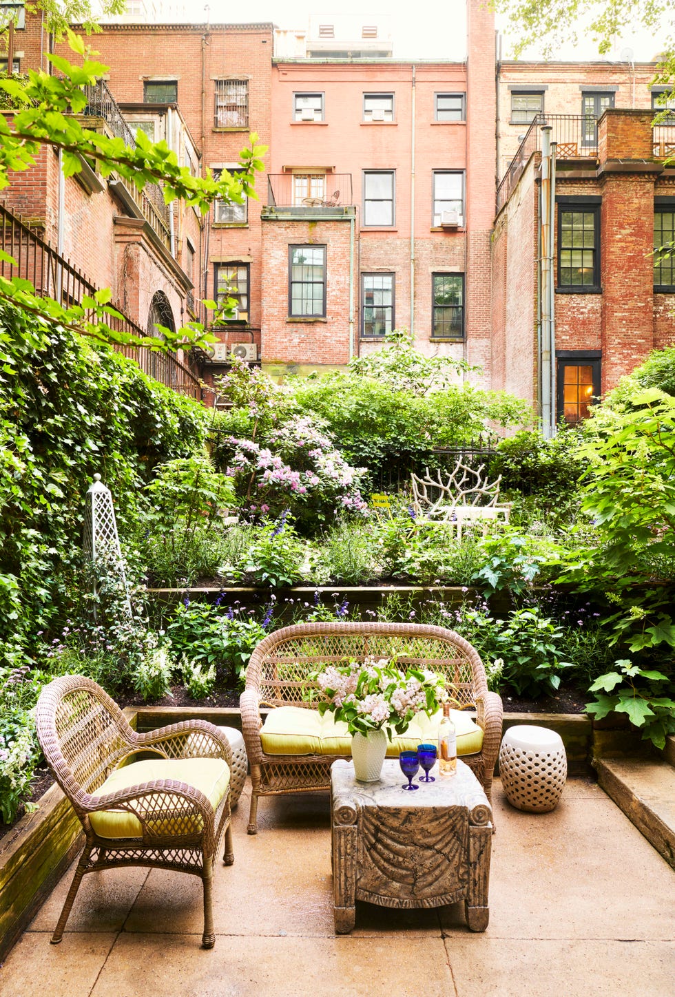 off the eerdmans ground floor bedroom is a private garden ensconced in oak leaf hydrangea, salvia, and lollipop verbena surrounding two wicker love seats and a table