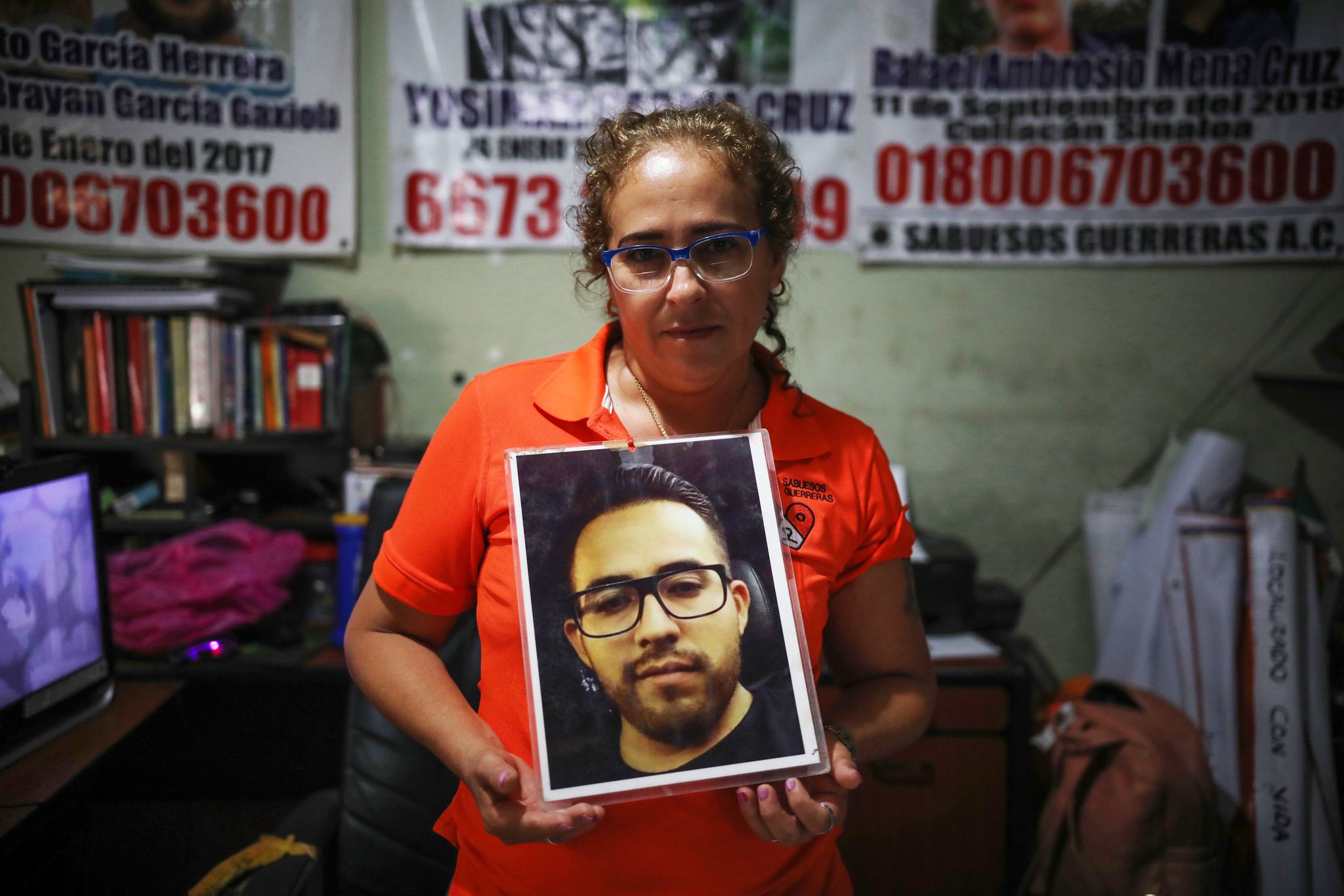 isabel cruz, founder of sabuesos guerros, holds up a photo of her son, yosimar, who has been missing for several years