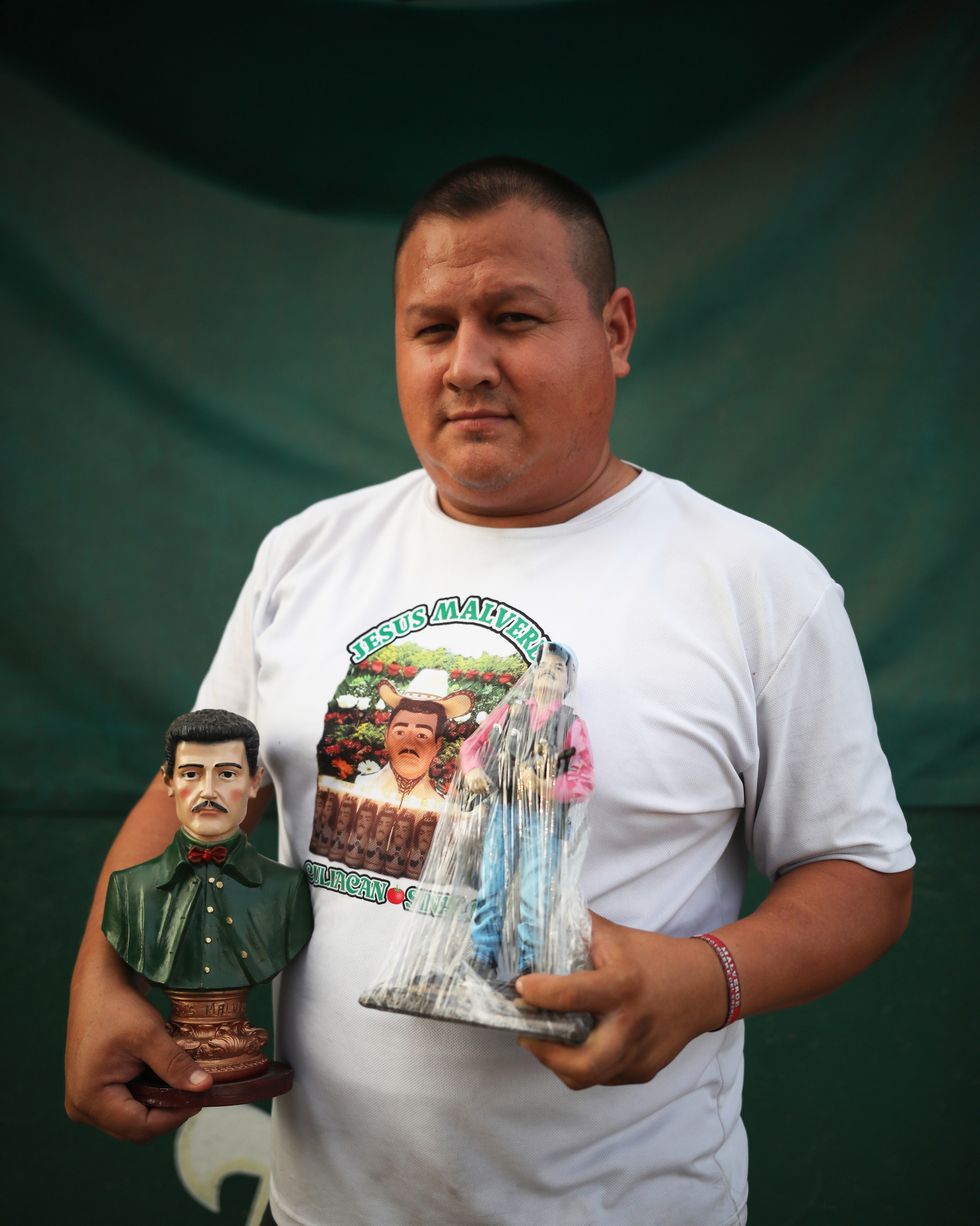 a vendor at the malverde shrine shows off his wares
