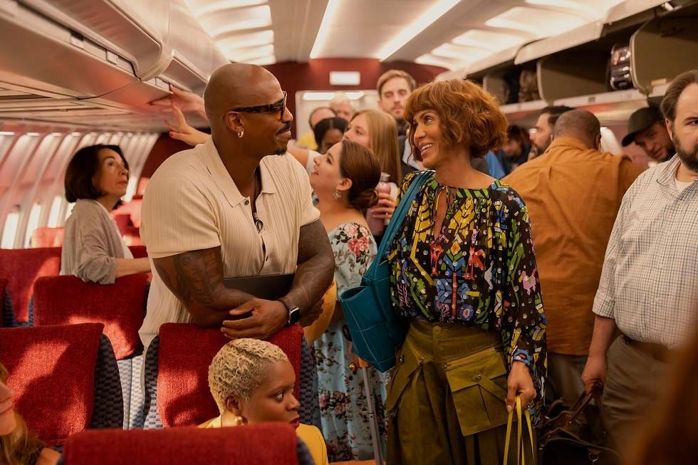 Passengers interacting and moving in the narrow aisle of a bus or train.