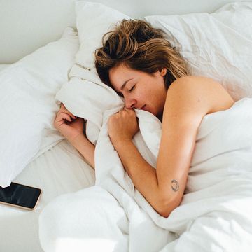 Vrouw ligt te slapen in bed met telefoon naast haar hoofd