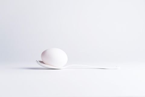 egg on spoon over white background