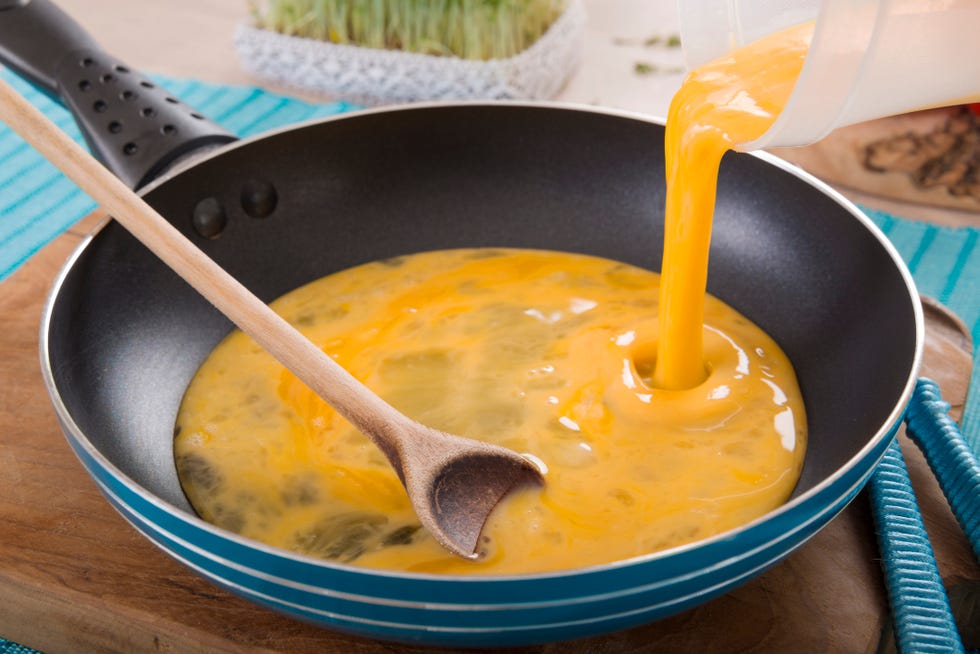 liquid egg for scrambled eggs is being poured into frying pan
