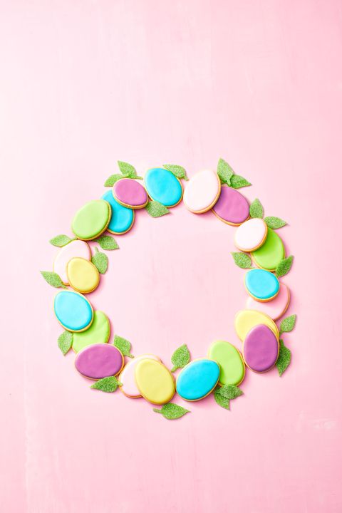 a colorful egg cookie wreath on a pink background