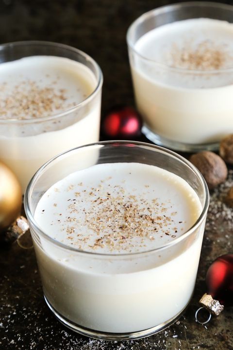 homemade eggnog with nutmeg in low glass with ornaments around