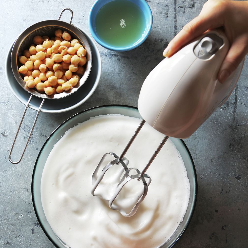 hand mixer whisking the liquid from a can of chickpeas in aquafaba