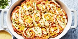 pinwheel style rolls baked in a casserole dish and topped with hollandaise