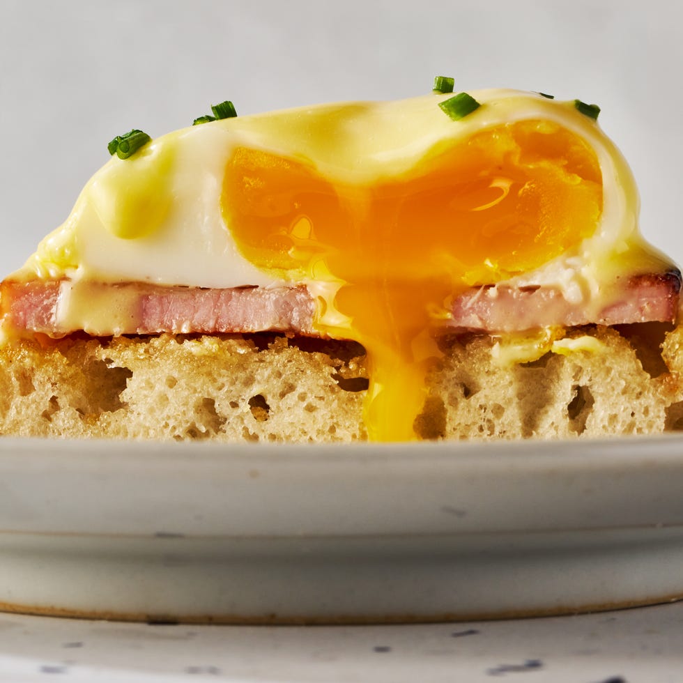 english muffins topped with ham, poached eggs and hollandaise on a plate