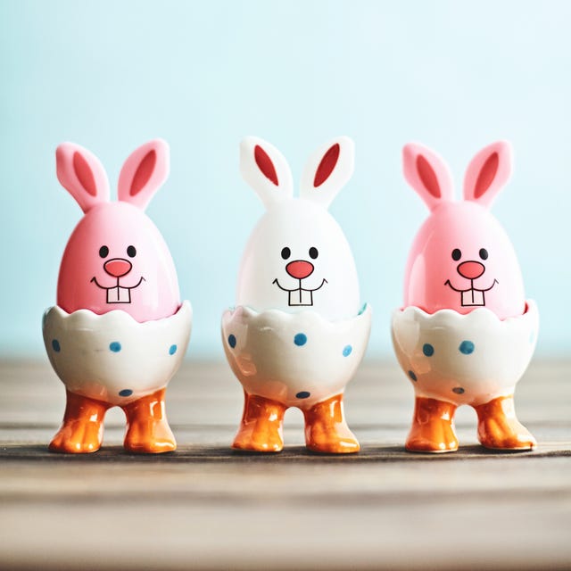 easter bunny trio in eggcups with blue background and rustic table top copy space for text