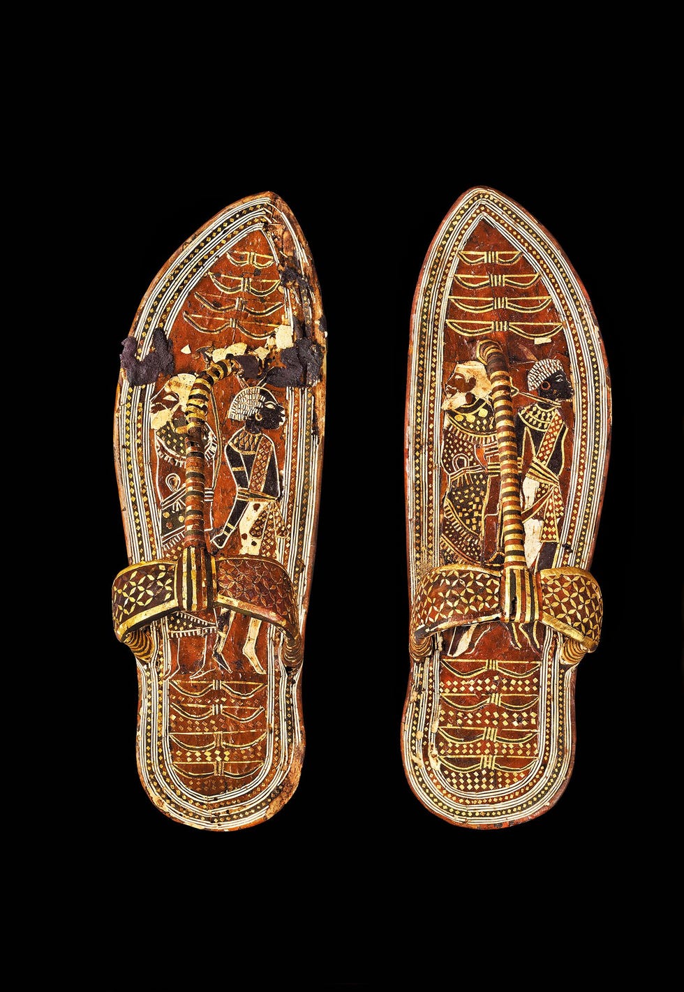 De schat die de wereld deed duizelen Toetanchamon was de laatste erfgenaam uit een familie van machtige heersers die Egypte tot een groot rijk hadden gemaakt Hij werd begraven met onder meer strijdwagens pijlen bogen schilden en ander wapentuigZijn mummie was uitgerust met twee dolken een van ijzer die mogelijk afkomstig was van een meteoriet en een van goud mogelijk een geschenk van een buitenlandse heerser Op de sandalen hierboven te zien zijn krijgsgevangenen afgebeeld waardoor de farao bij elke stap die hij zette de vijanden van Egypte symbolisch vertrapte Dit bed dat alleen voor begrafenisrituelen werd gebruikt is versierd met twee heilige koeien met een zonneschijf tussen de hoorns Het vergulde bed een van de drie die werden gevonden in de voorkamer van Toetanchamons tombe afgebeeld op de volgende paginas verbeeldt de mythe van MehetWeret de koegodin die Ra de zon elke dag naar de hemel droeg Er stonden nog zes andere bedden in de tombe Deze waren comfortabeler zodat de koning goed kon rusten in het hiernamaals