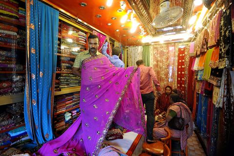 Een verkoper stalt prachtig geborduurde saris uit in een textielwinkel in Dhaka Ramadan is een van de drukste tijden voor de winkeliers omdat nieuwe kleding een populair geschenk is tijdens het Suikerfeest