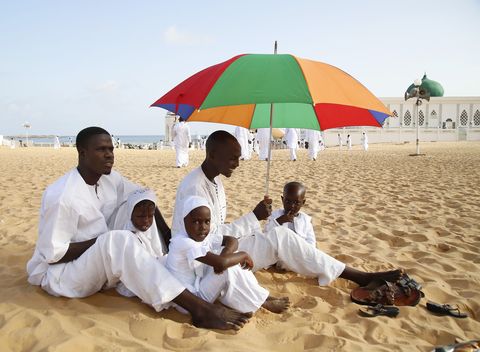 Een familie zit op het strand in Dakar in Senegal in afwachting van het gebed in het nabijgelegen Mausole de Seydina Limamou