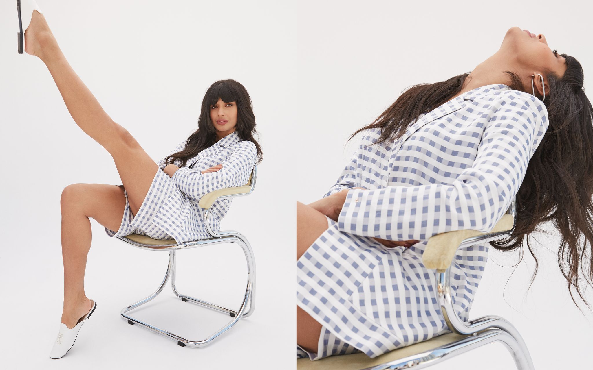 jameela jamil sitting with her leg in the air on a retro chair against a white backdrop, wearing a blue and white checked blazer and shorts and white backless loafers