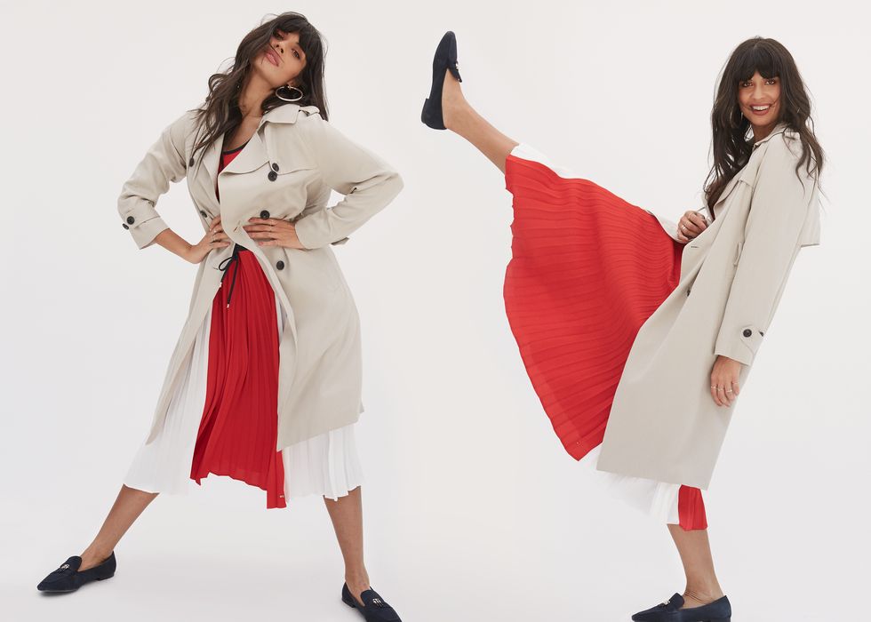 jameela jamil poses playfully against a white backdrop wearing a beige trench, red and white dress and blue loafer shoes, all by tommy hilfiger
